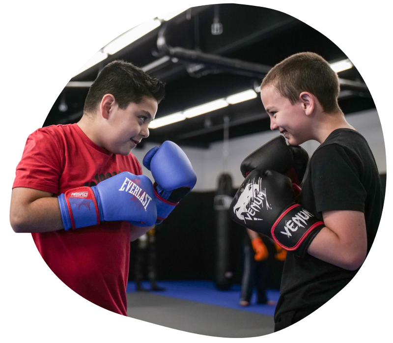 Two young boys are smiling as they participate in our MMA program